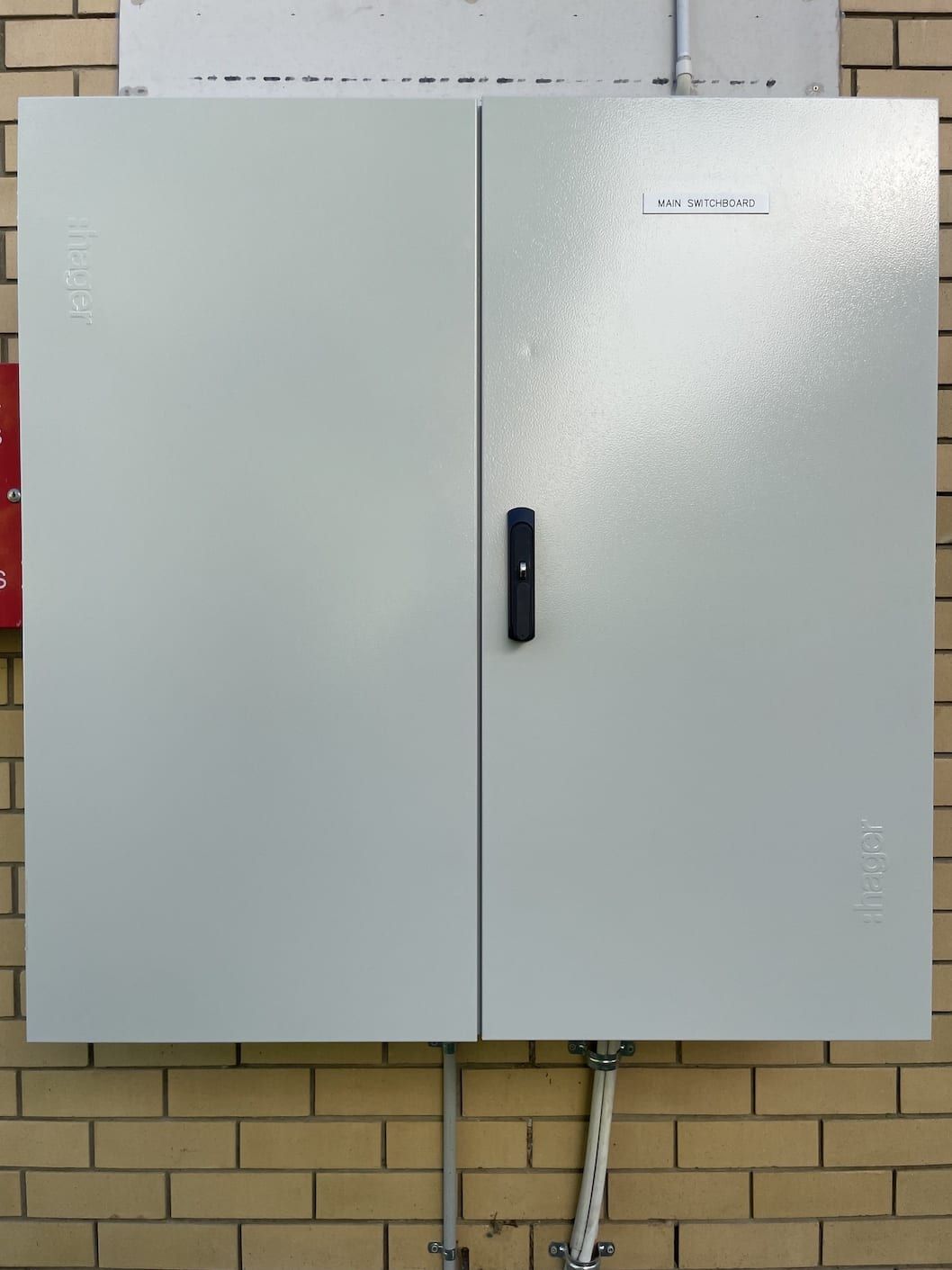A white cabinet with a black handle on a brick wall