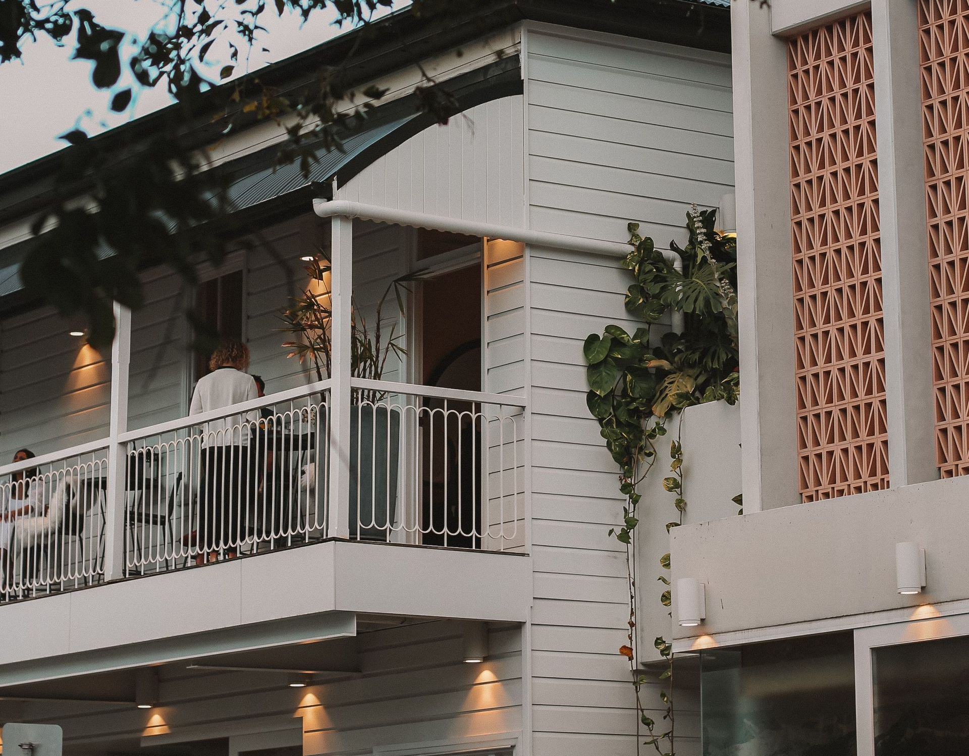 Balcony with white railing and green vines on a modern house exterior at dusk