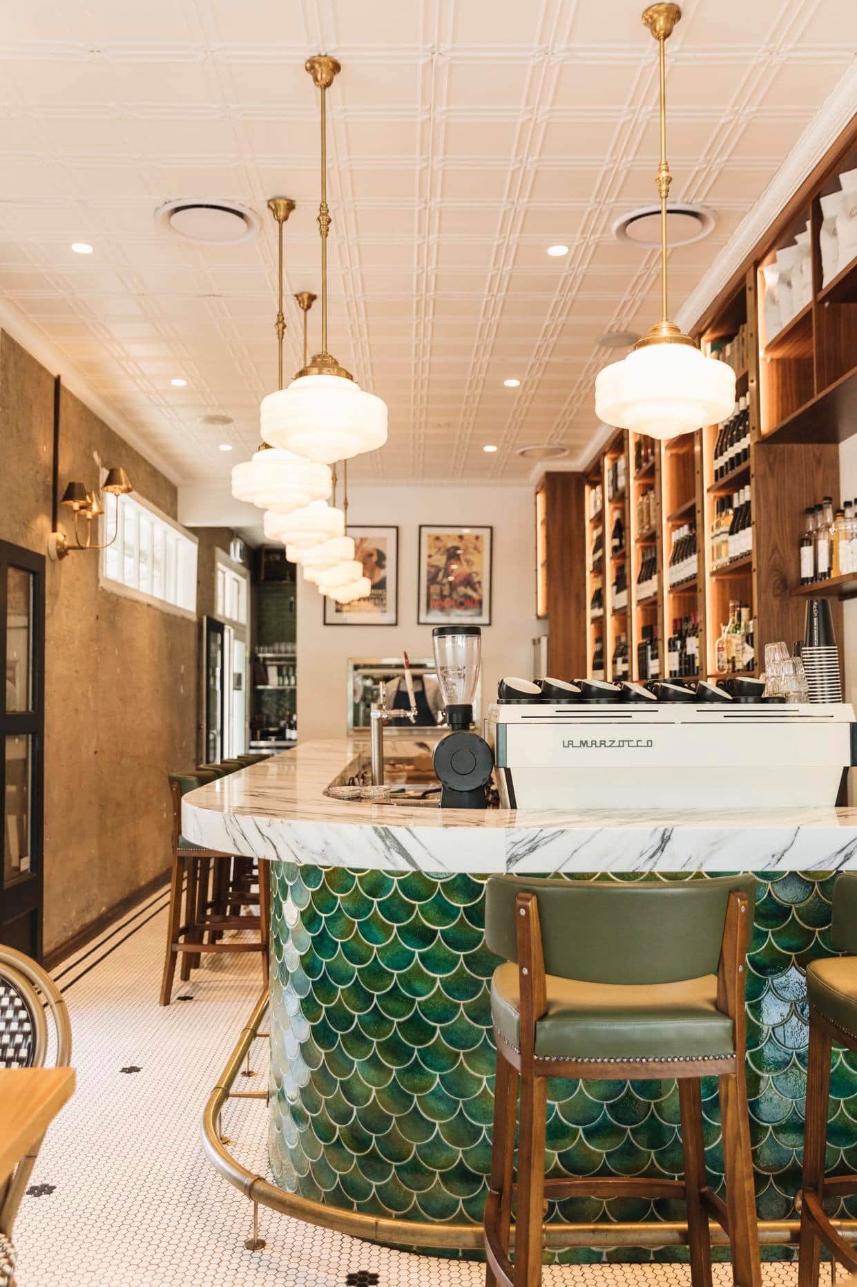 A bar in a restaurant with a green counter top and stools.