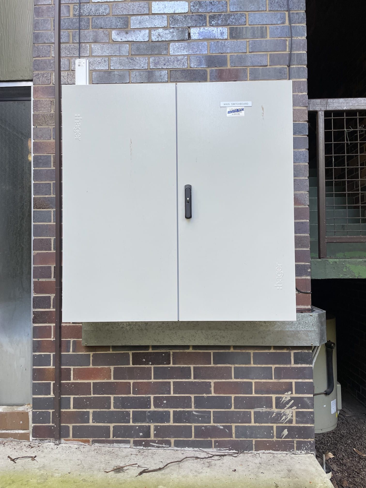 A white cabinet is hanging on a brick wall.
