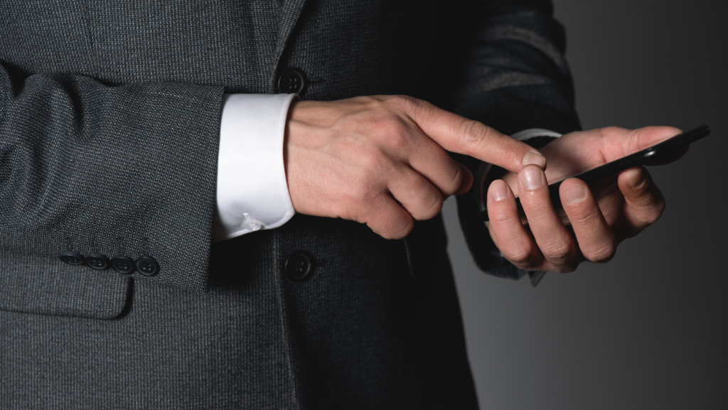 A man in a suit is using a cell phone.