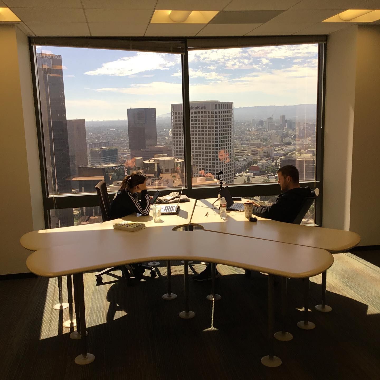 two people sit at a table in front of a large window