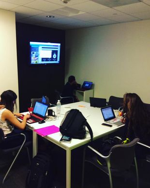 a group of people sitting around a table with laptops