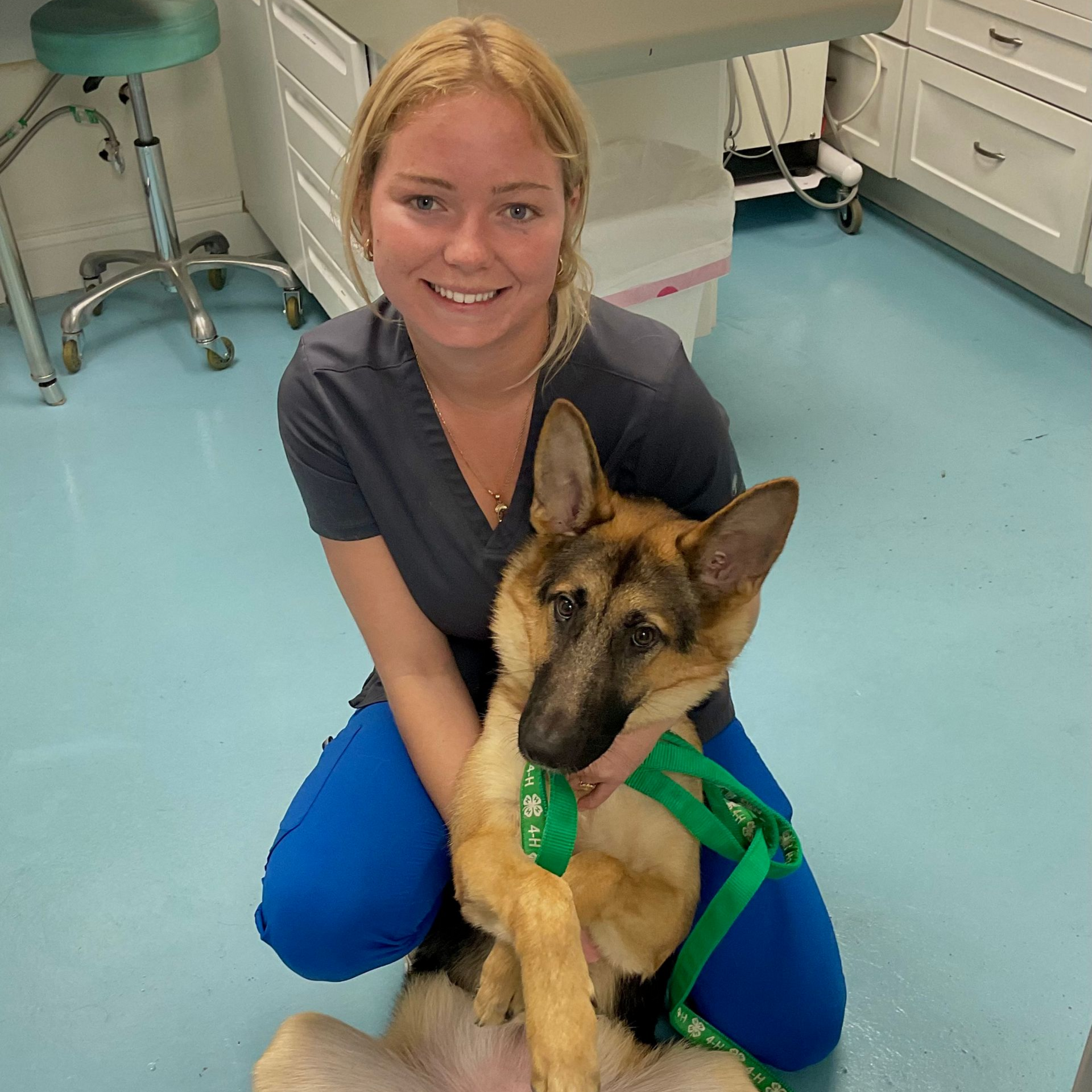 Woman with blonde hair holding a German Shepherd, smiling.