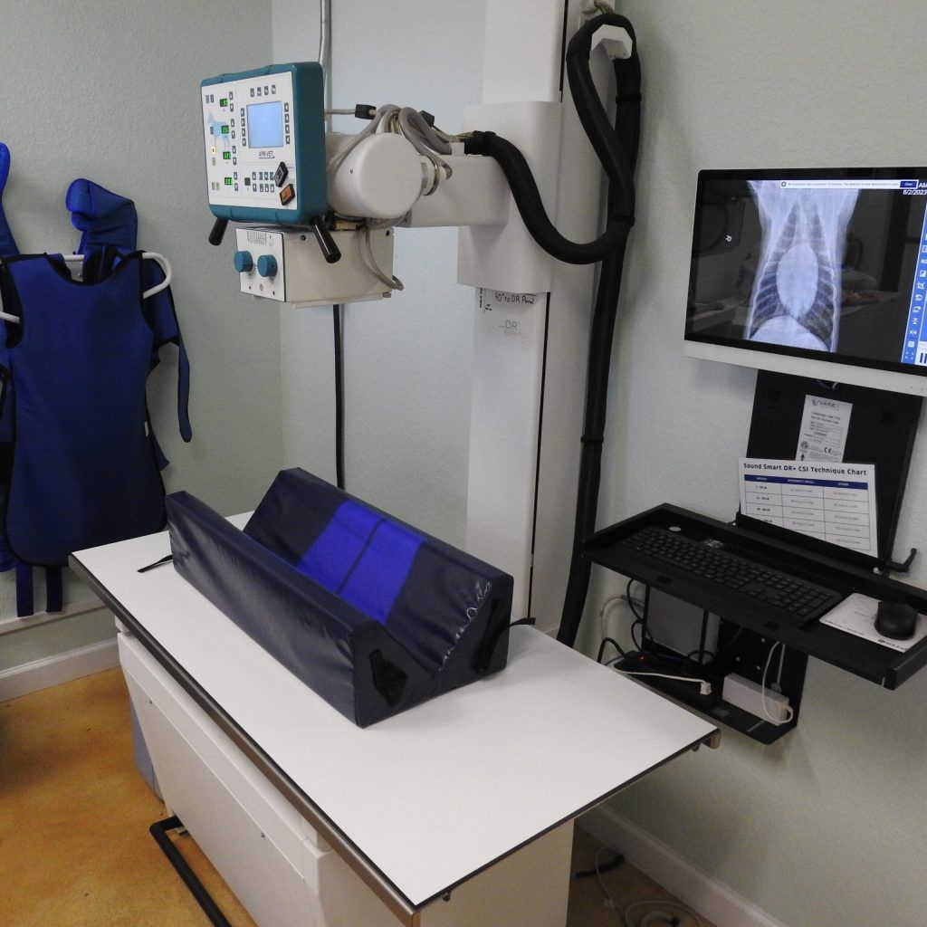 An x-ray machine is sitting on a table next to a computer monitor