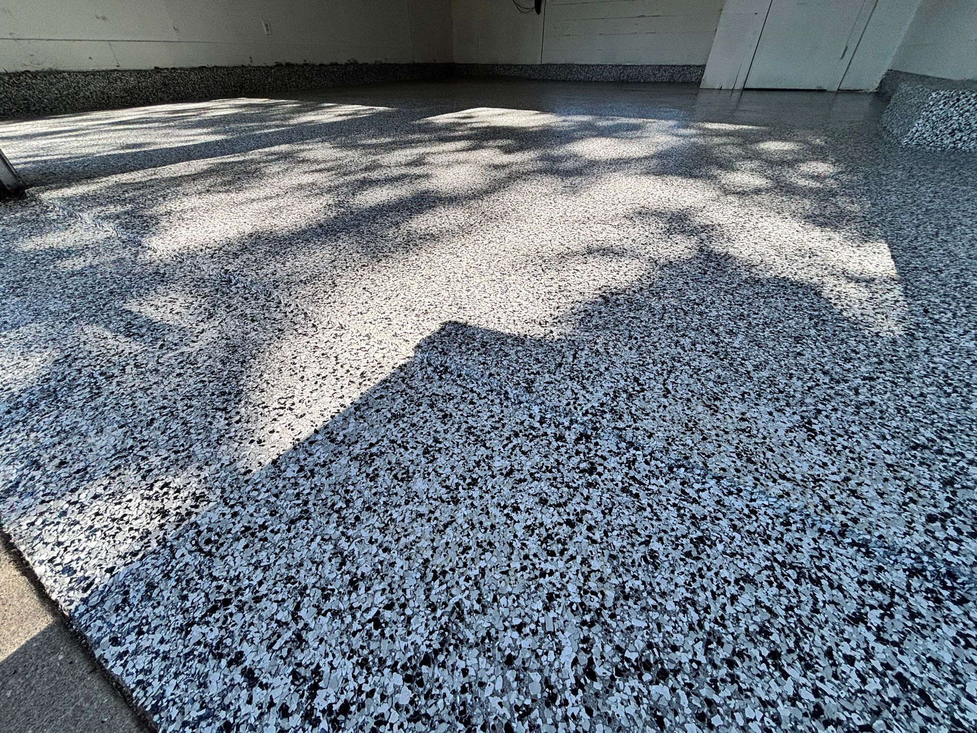 Garage floor with speckled epoxy coating in shades of gray.