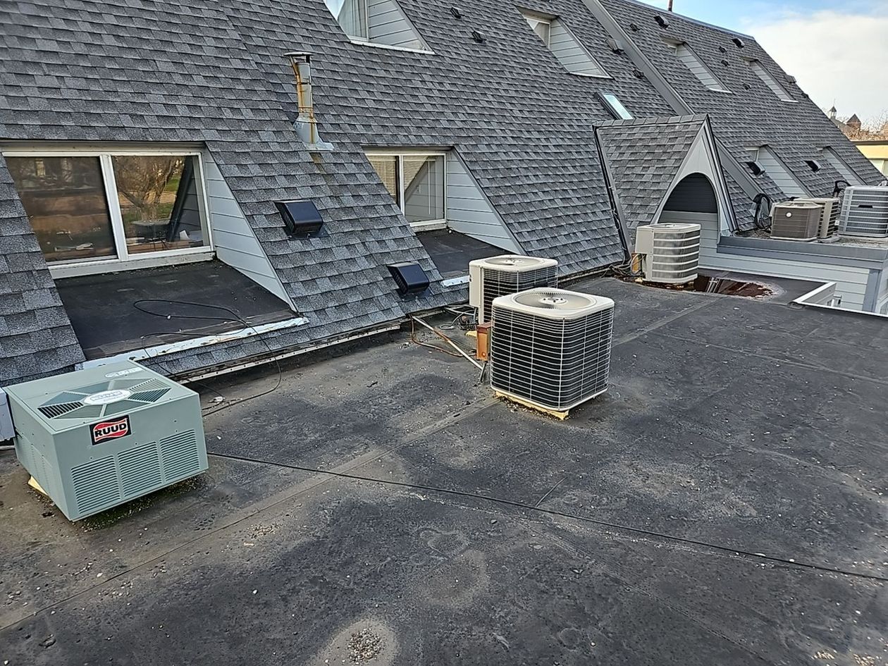 there are two air conditioners on the roof of a building .