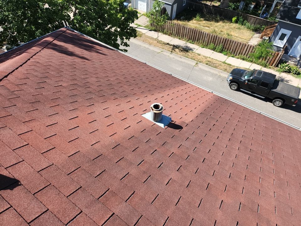 a red roof with a black truck parked on the side of the road .