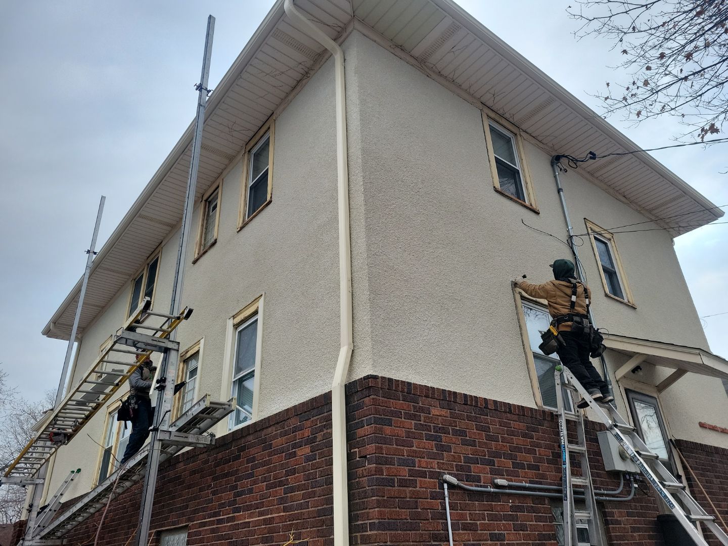 a man is standing on a ladder on the side of a building .