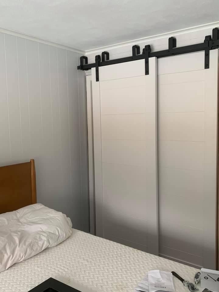 Bedroom with white sliding barn doors and a bed with white bedding near the wall