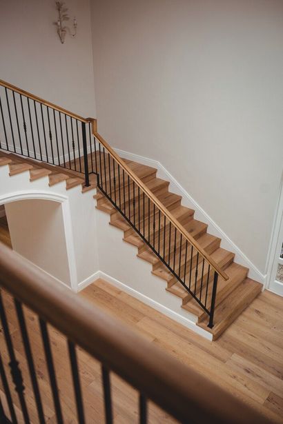 Indoor staircase with wooden steps, black railing, and light walls in a home interior.