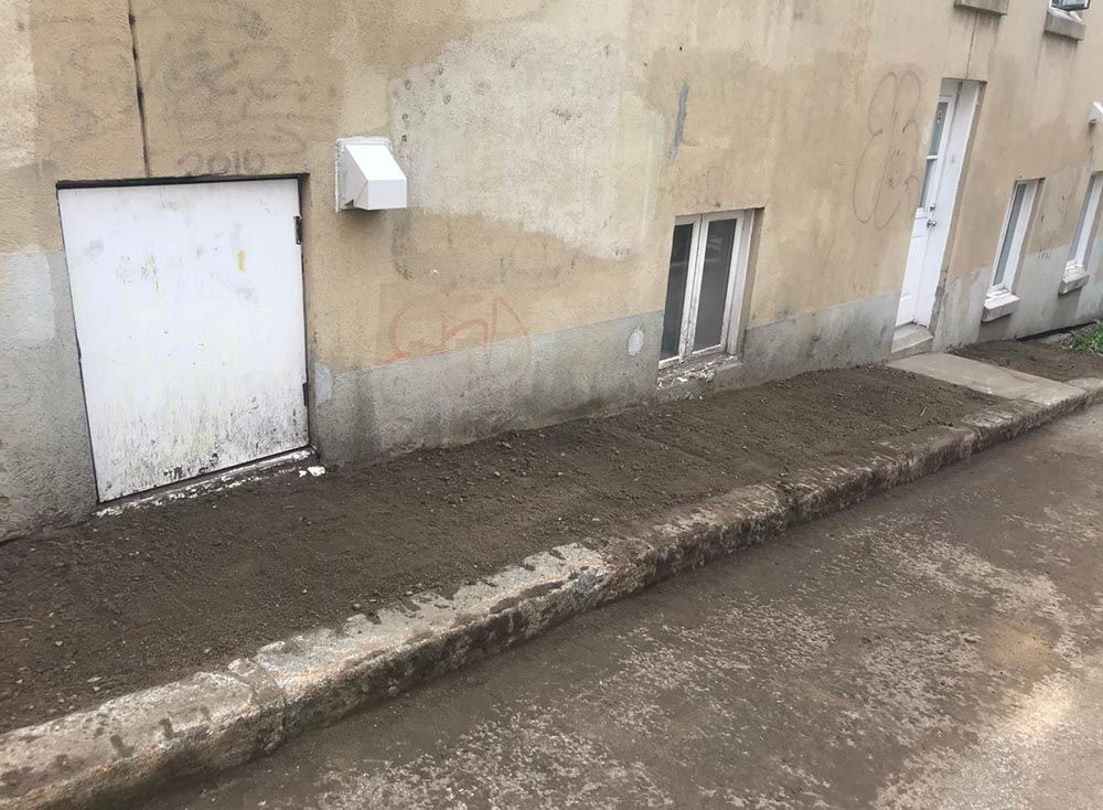 Un trottoir sale devant un immeuble avec une porte de garage.