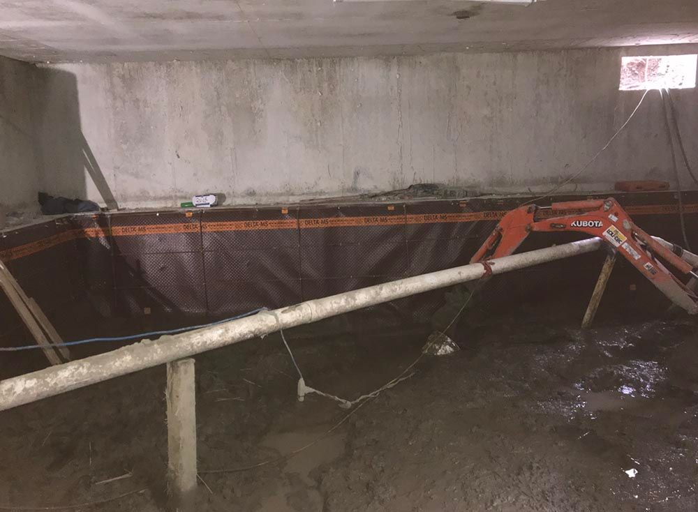 Un sous-sol inondé avec une échelle et des tuyaux à l'intérieur.