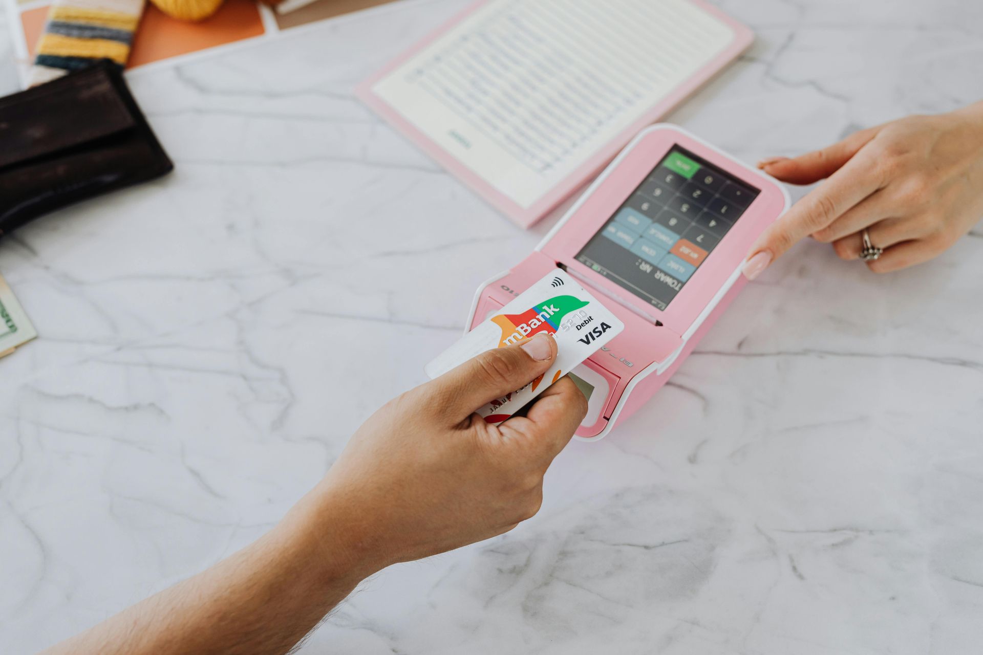 A person is using a pink credit card machine to pay for something.