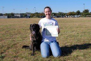 woman and black dog in the field with certificate - Bastrop, TX - K9 Mastery