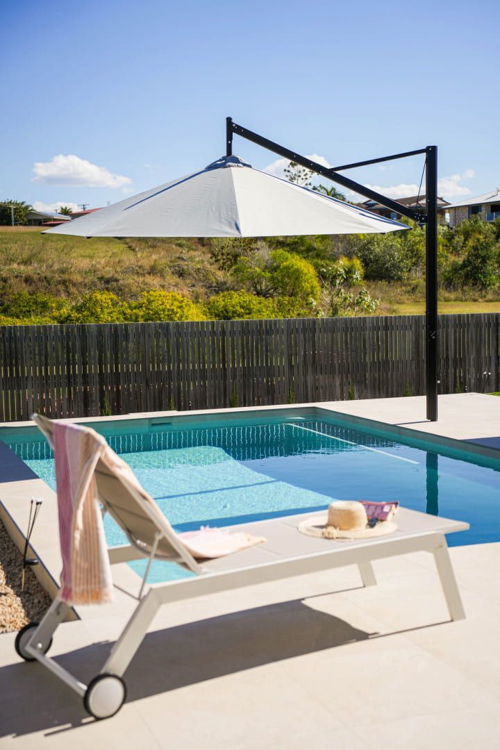 Poolside Scene: White Cantilever Umbrella Shades a Lounge Chair — Concrete Pool Projects in Gladstone Central, QLD