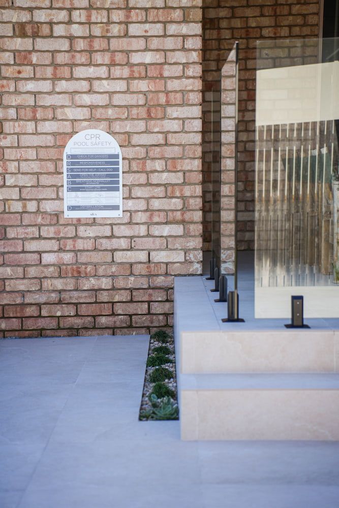 Brick Wall With Glass Panels, Steps, and Landscaping — Concrete Pool Projects in Gladstone Central, QLD
