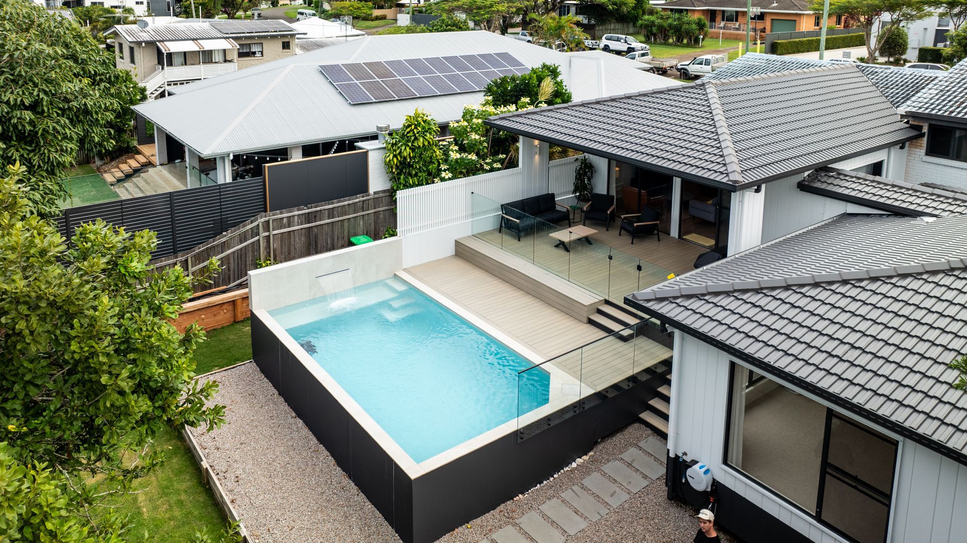 Aerial view of a modern house with a small pool, outdoor deck, and solar panels on the roof — Concrete Pool Projects in Gladstone Central, QLD