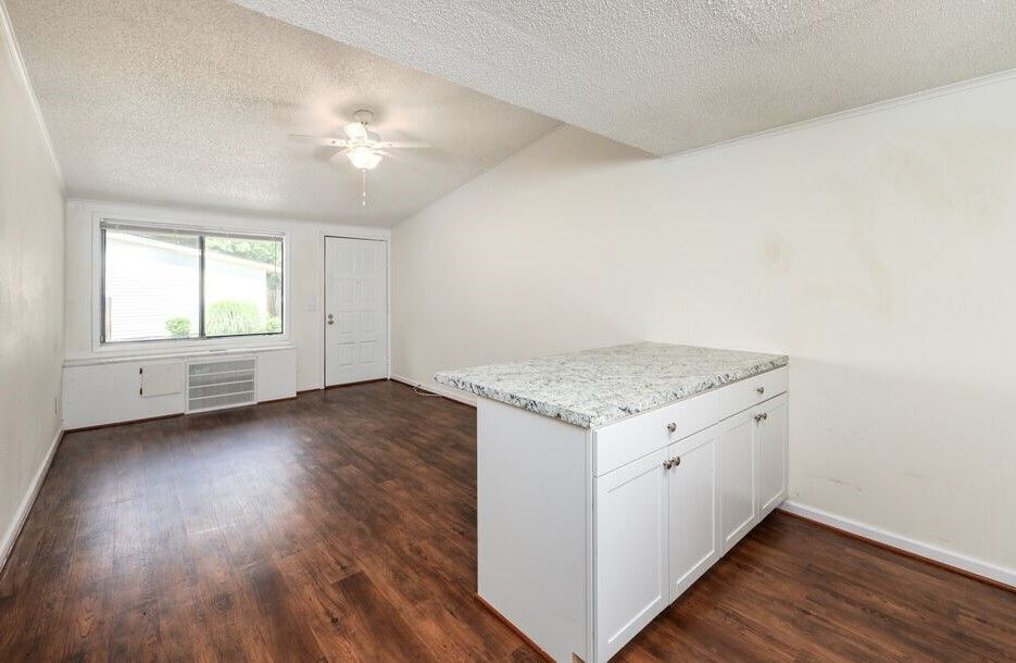 Photo of a living room, seen from the kitchen, with plenty of sunlight coming in