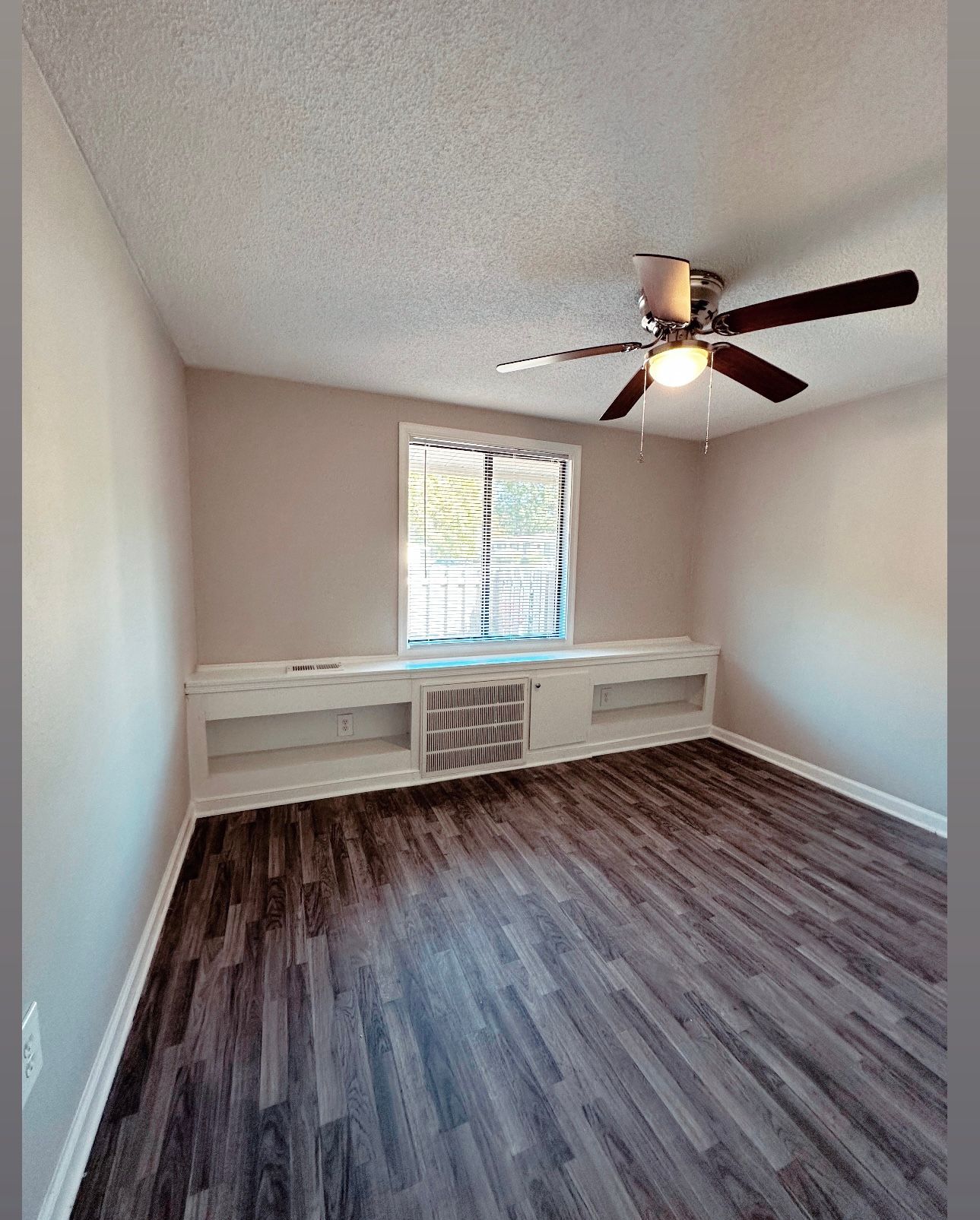 Photo of a bedroom with a ceiling fan and a tall window