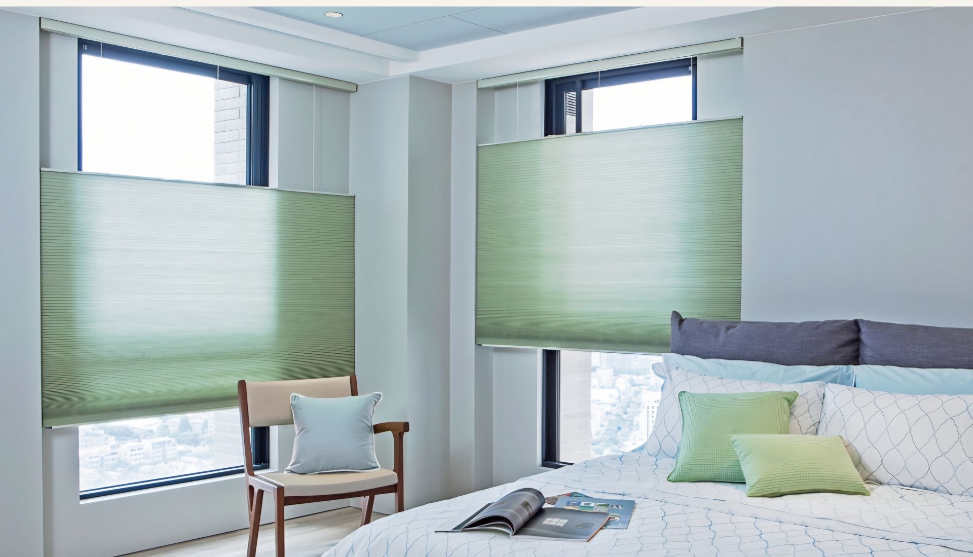 Bedroom with green pleated blinds, a chair, and a bed with pillows.