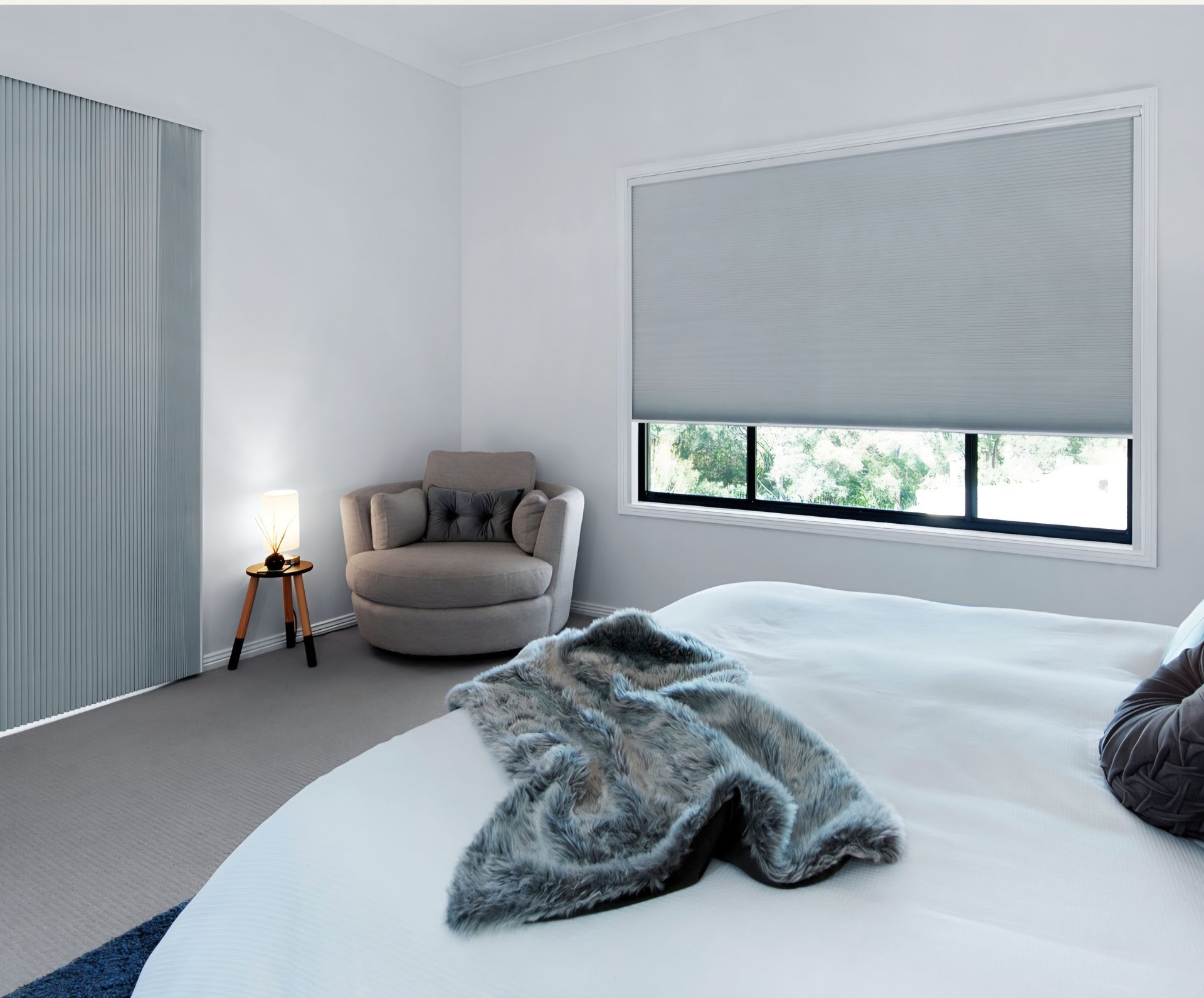 Bedroom with bed, chair, window with blinds, and curtains. Gray and white color scheme.
