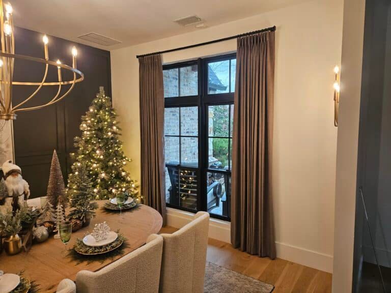 Elegant dining room with a Christmas tree, window with gray curtains, and chandelier.
