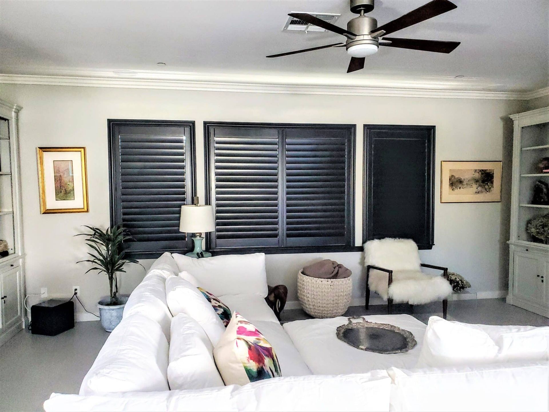 Living room with white sectional sofa, black shutters, and light gray walls.