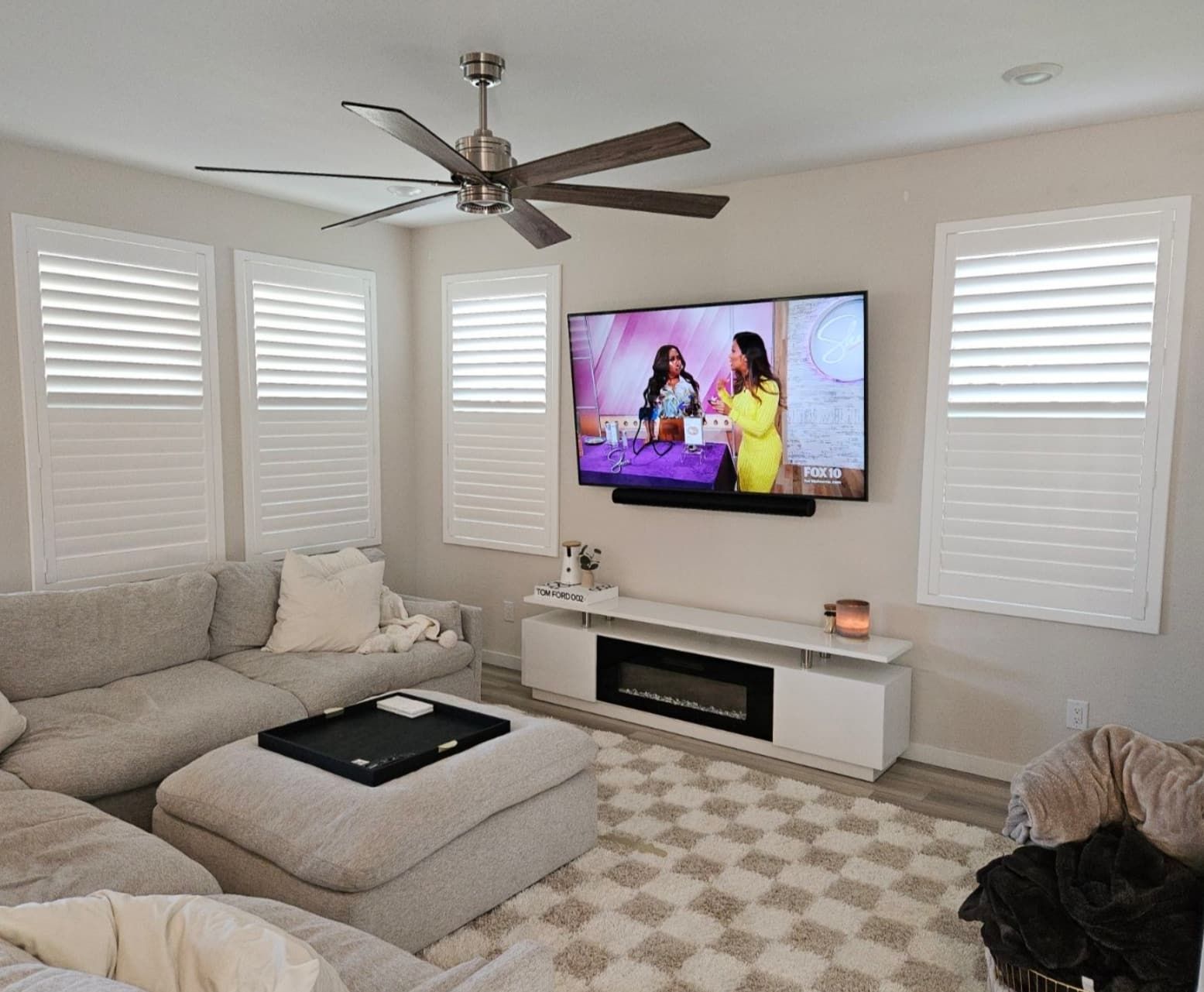 Living room with sectional sofa, TV, fireplace, and window shutters.