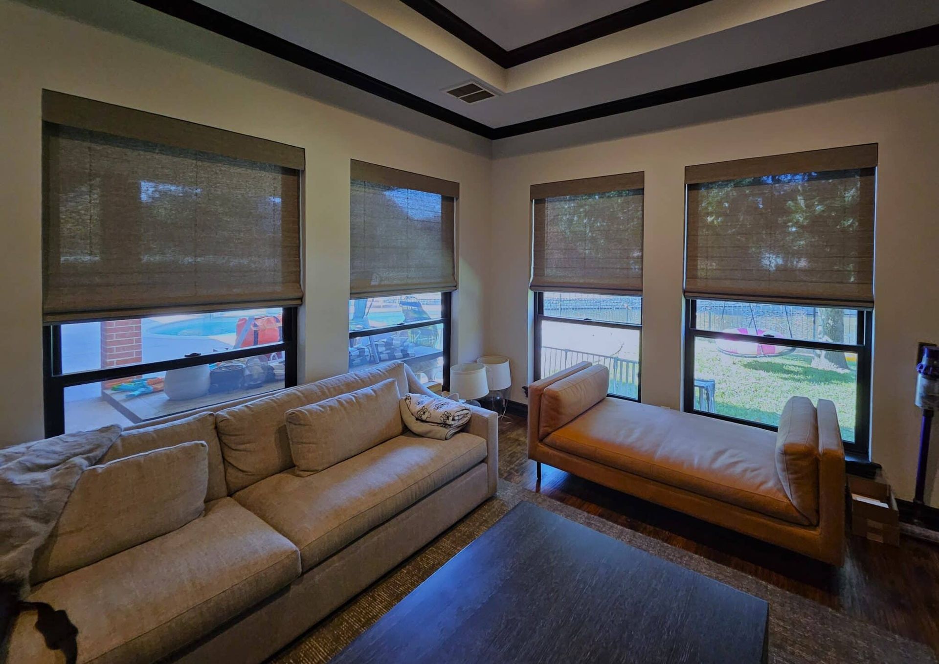 Living room with a sofa, chaise lounge, and three windows with shades.