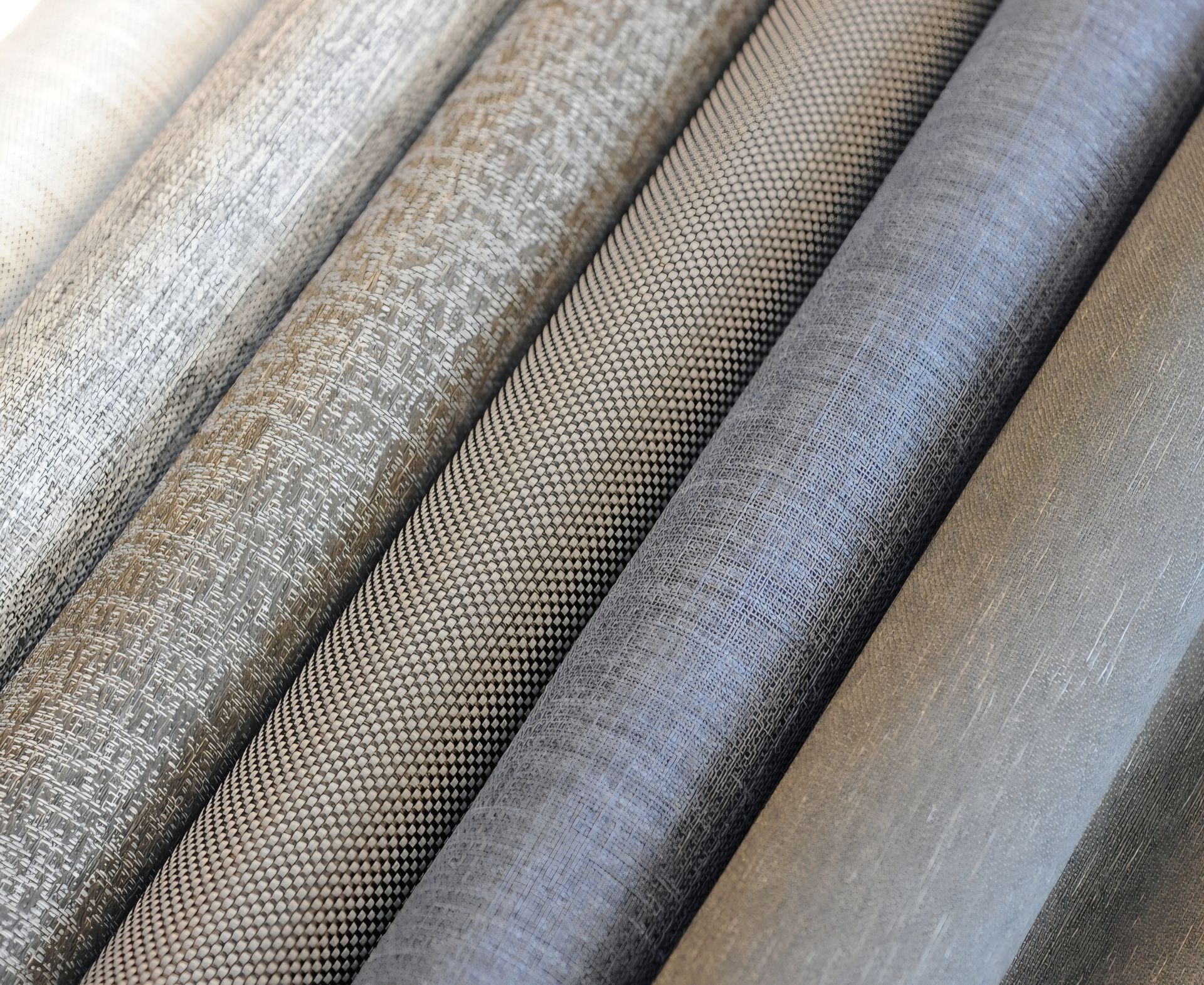Rolled fabric samples in various textured gray and beige tones.