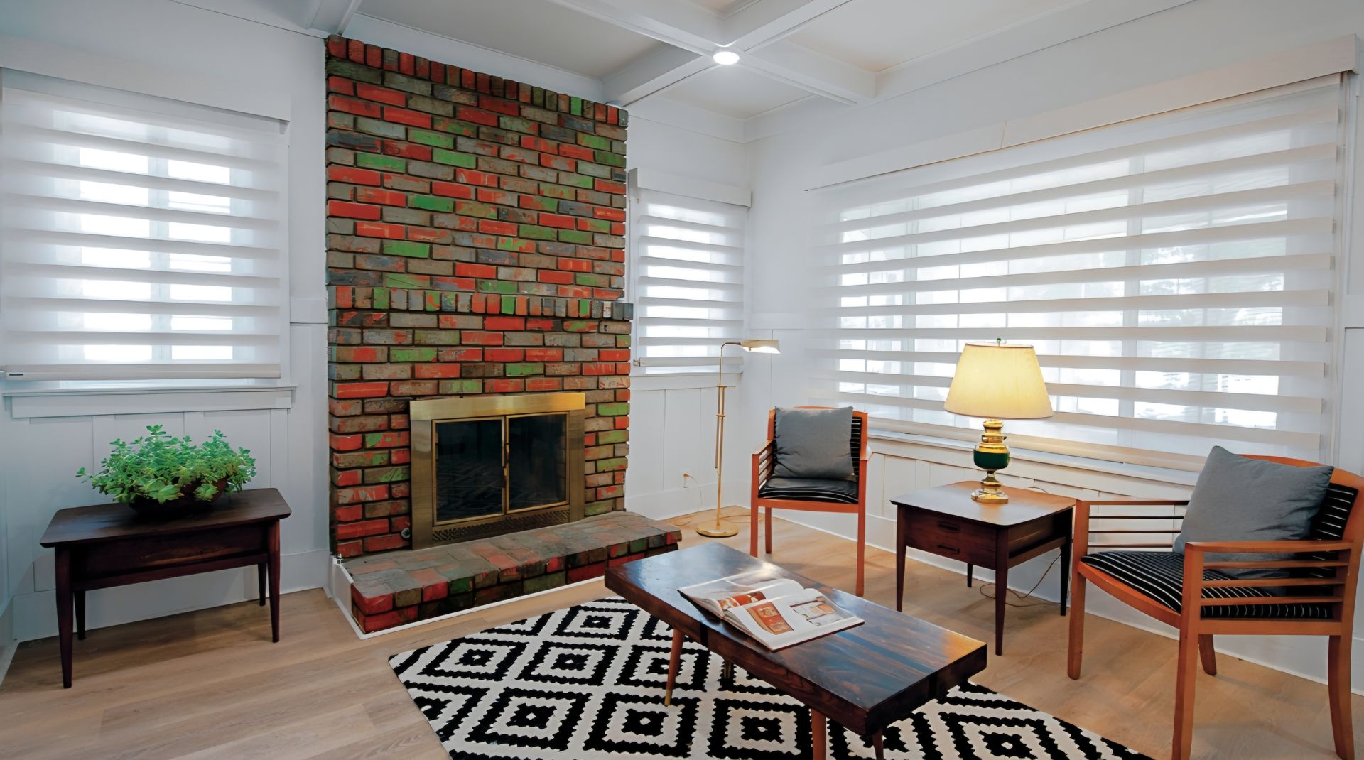 Living room with brick fireplace, sheer window shades, and mid-century modern furniture.