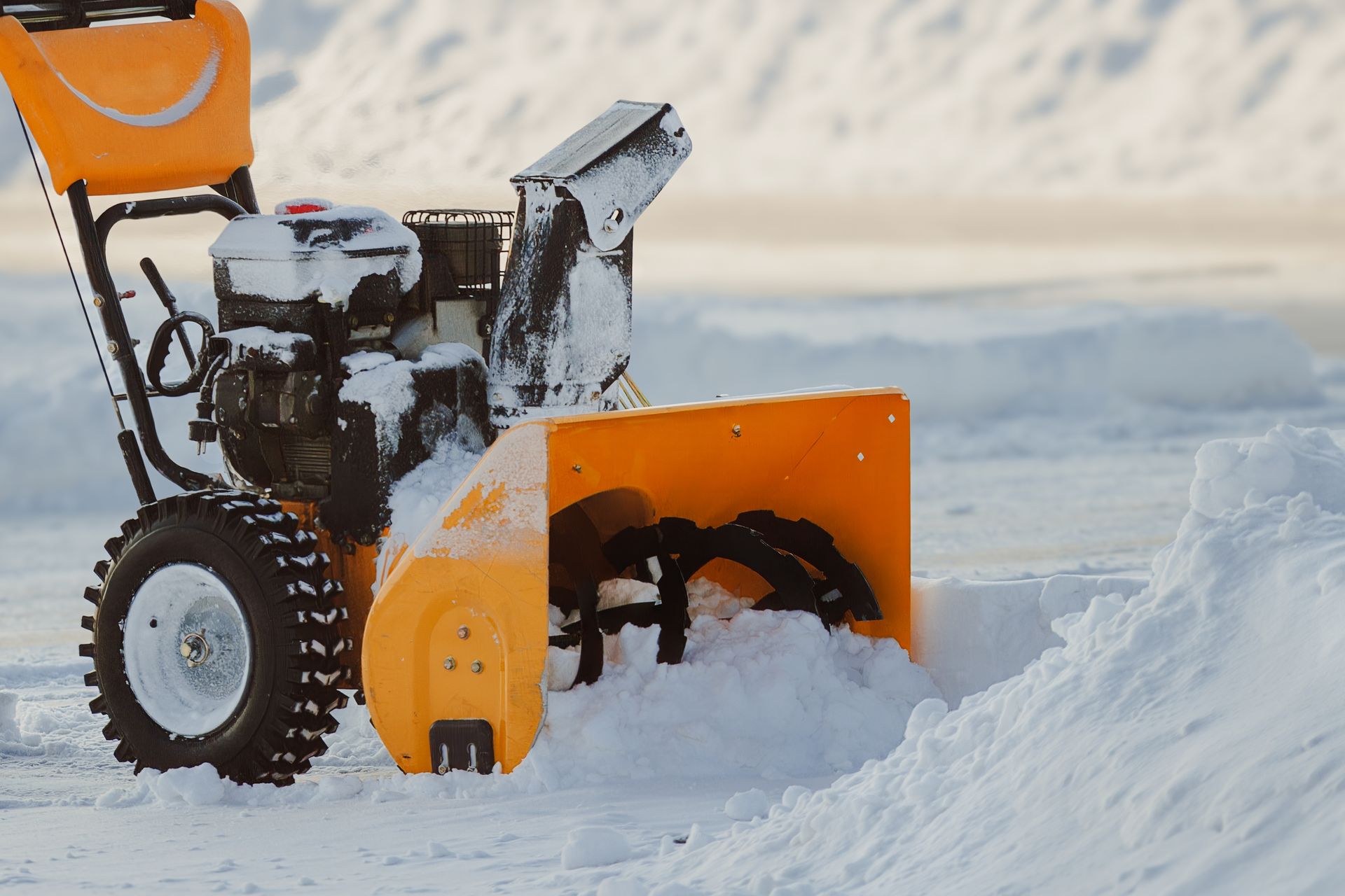 Orange snowblower clearing deep snow outdoors in a snowy landscape