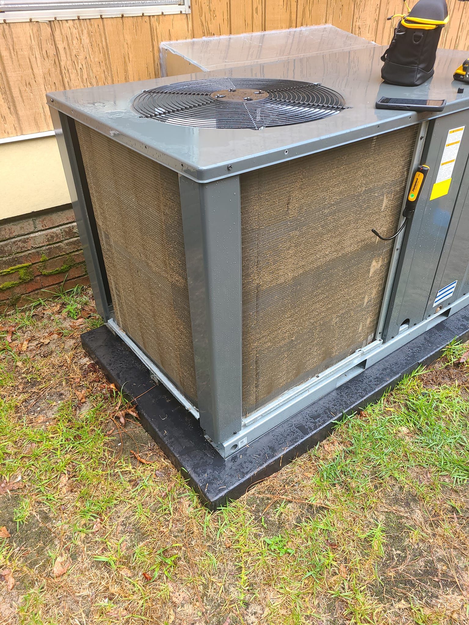 Woman in straw hat smiles, holding wine glass near a lake.