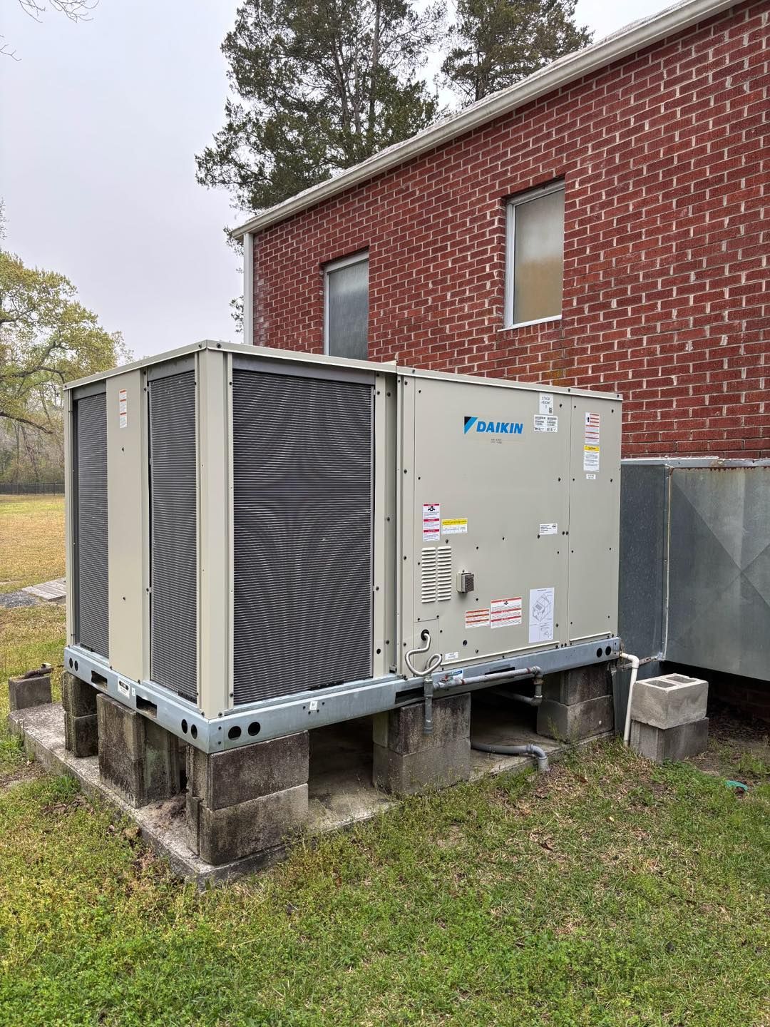 Woman in straw hat smiles, holding wine glass near a lake.