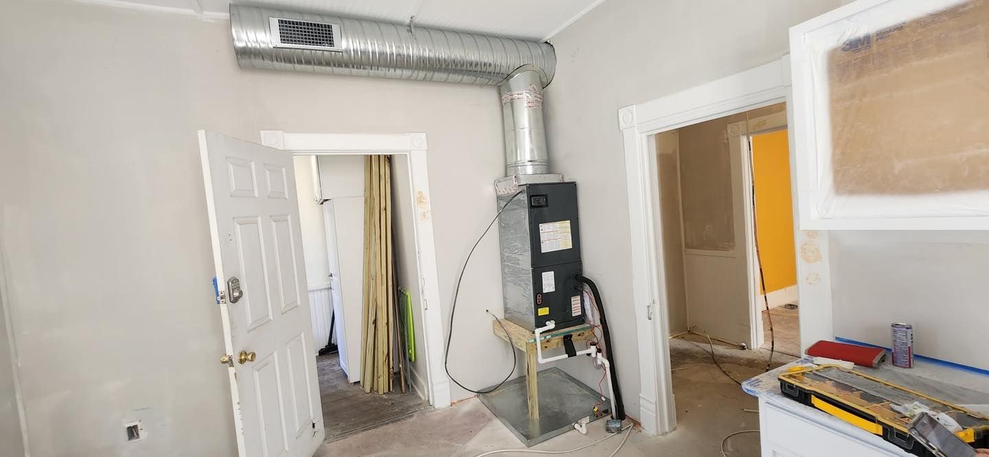 Crane lifting an HVAC unit onto a rooftop on a sunny day.