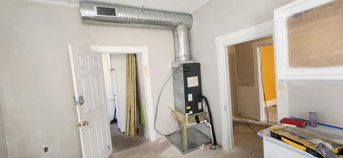 Crane lifting an HVAC unit onto a rooftop on a sunny day.