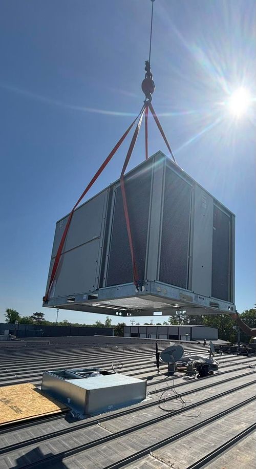 A flatbed truck with a crane extended upwards; a person stands nearby.