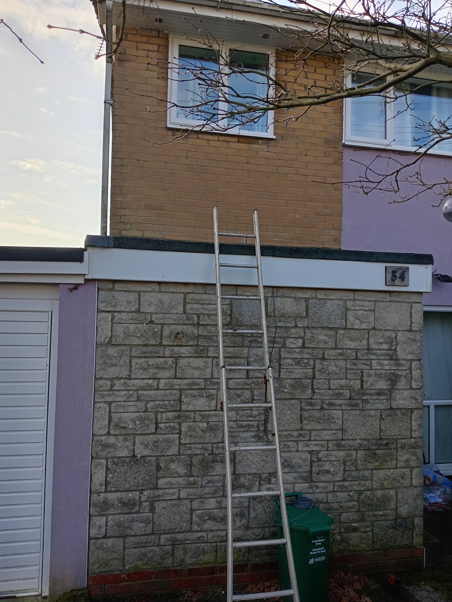 A ladder is sitting on the side of a brick building.