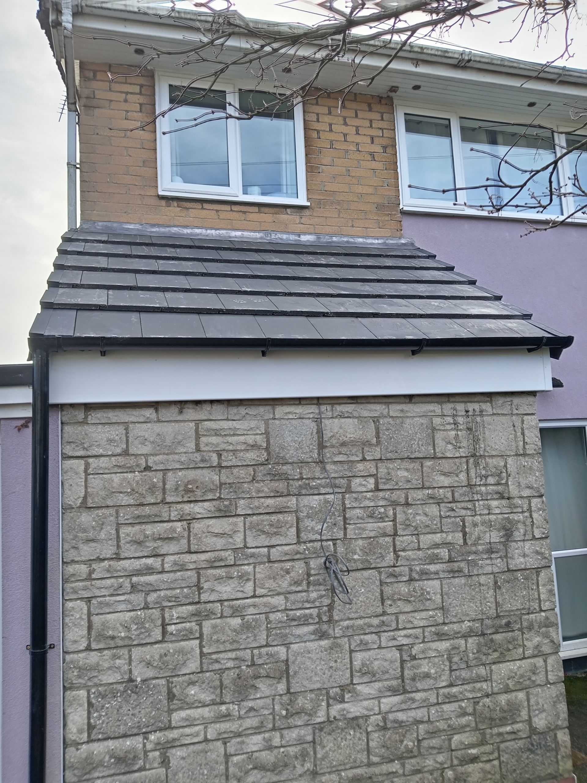 A house with a stone wall and a roof