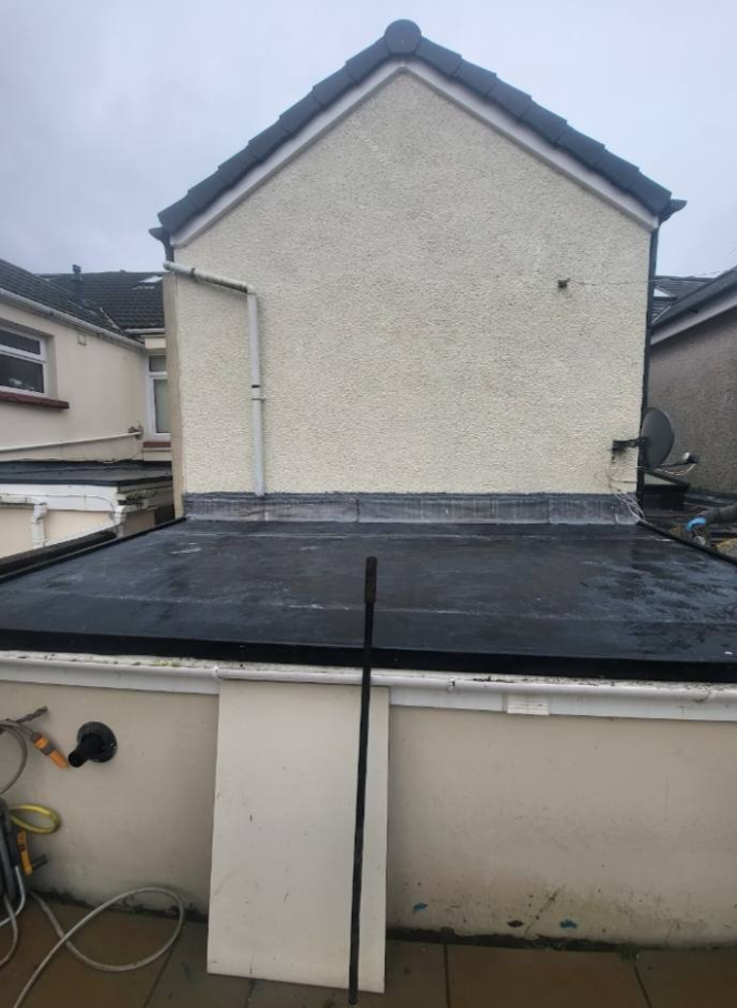 A house with a black roof and a white wall.