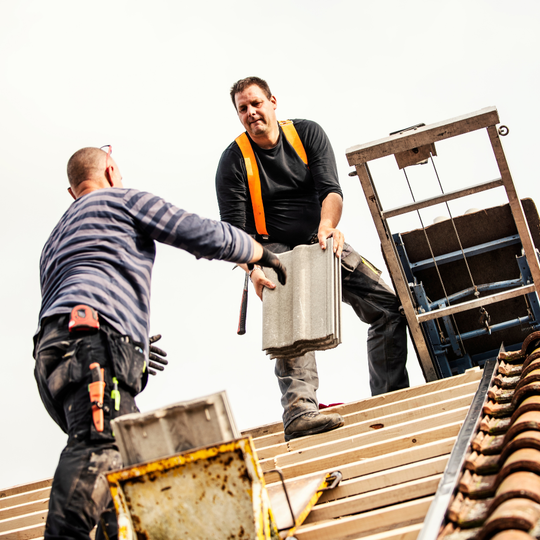 Two men are working on the roof of a building