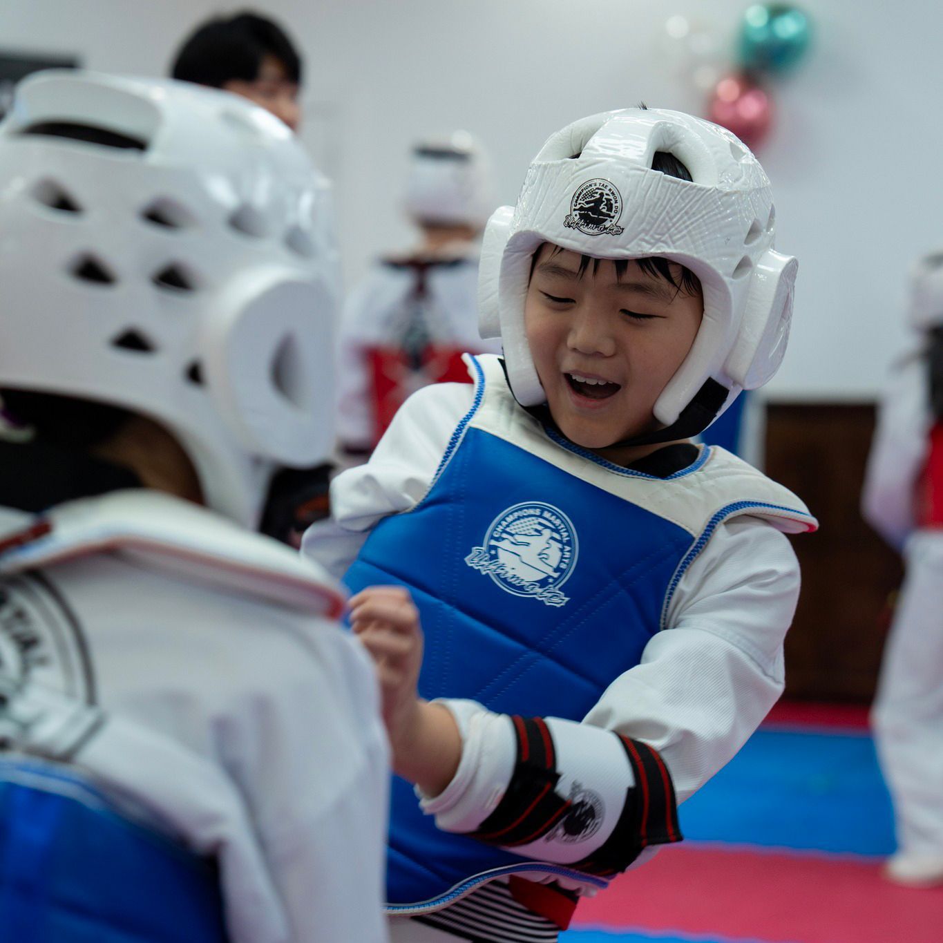 A young boy wearing a taekwondo vest and helmet