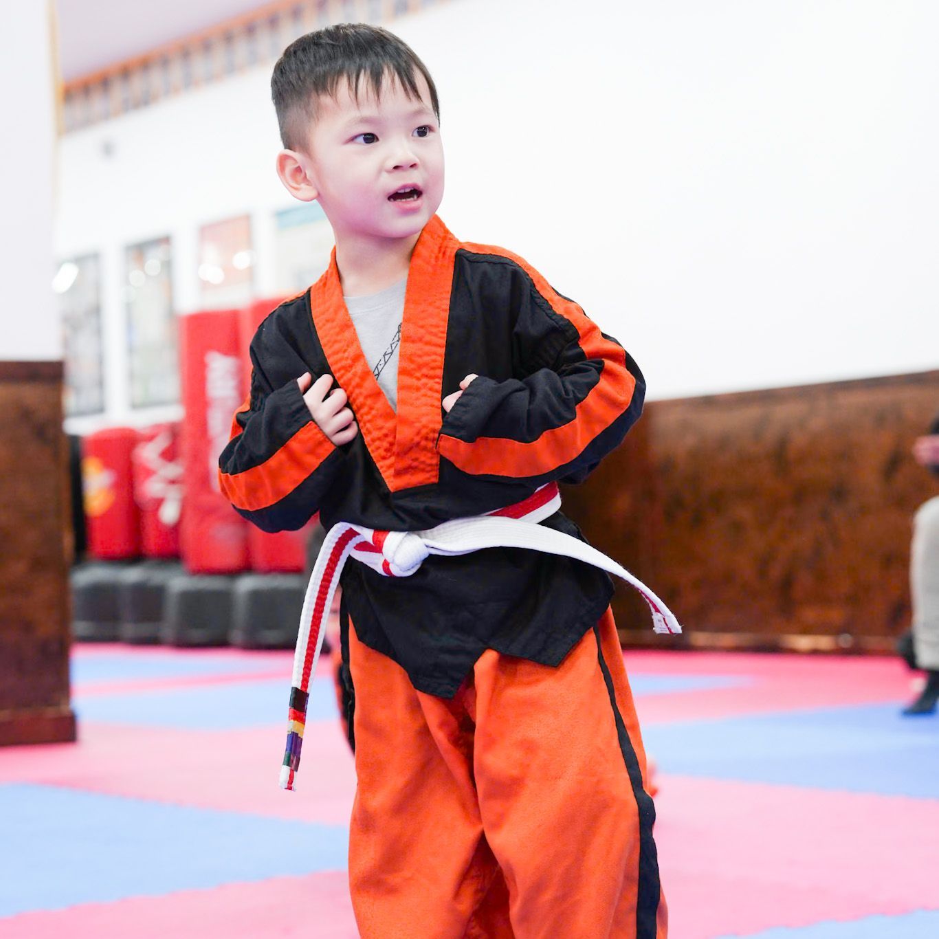 A young boy wearing a black and orange karate uniform