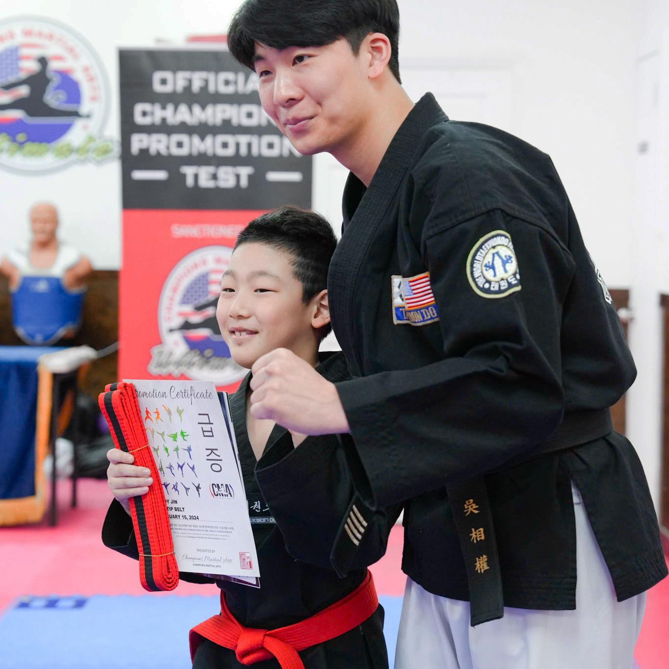 A man and a boy are standing in front of a sign that says official champion promotion test