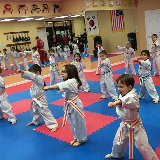 A group of children are practicing martial arts in a gym