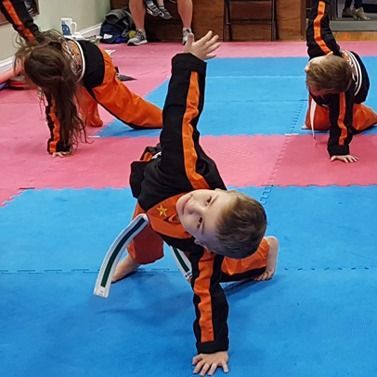 A boy is doing a handstand on a mat in a gym.