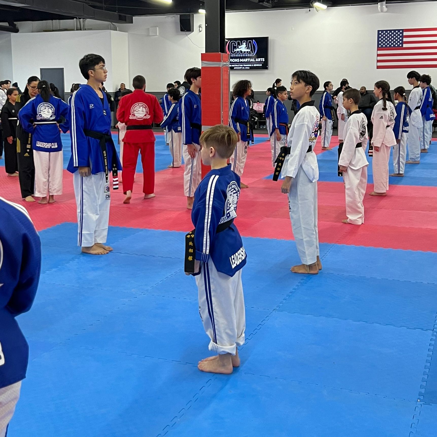 A group of people are standing in a room with an american flag on the wall