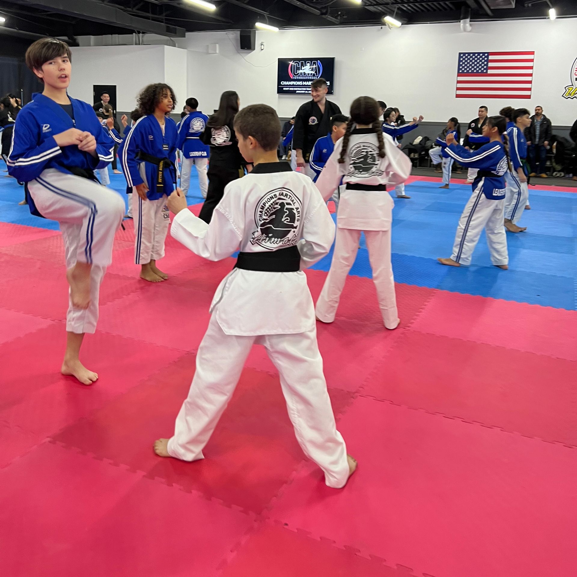 A group of children are practicing martial arts on a pink mat.