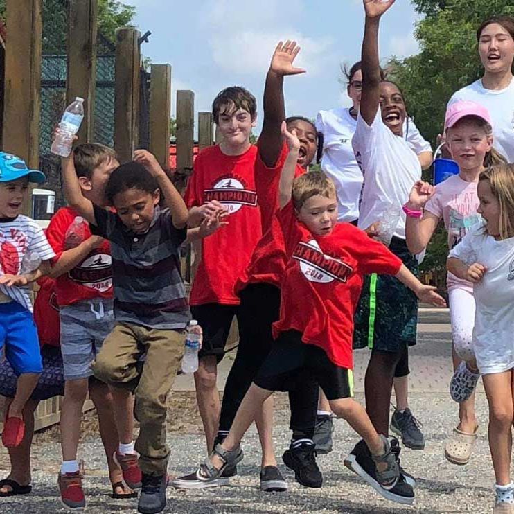 A group of children are standing next to each other with their hands in the air.